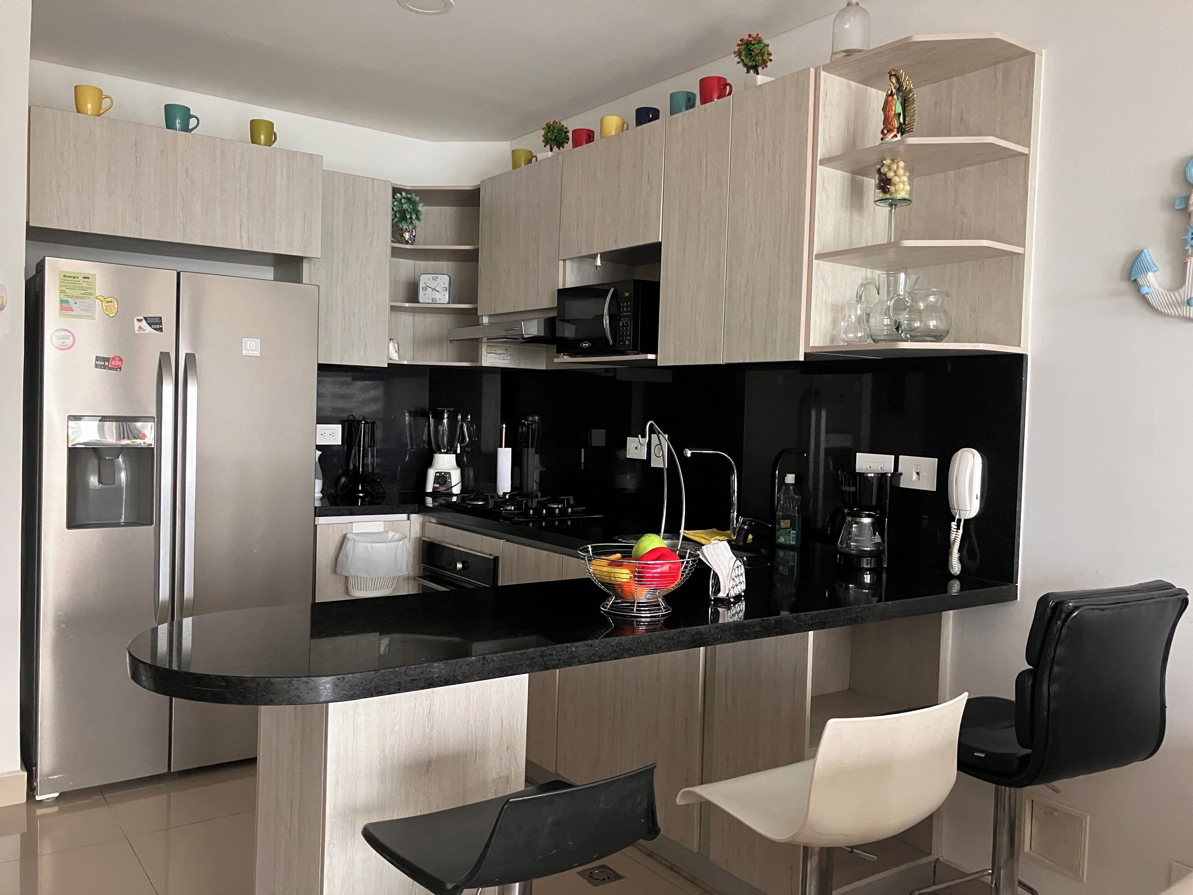 Una cocina moderna con una isla central, electrodomésticos de acero inoxidable y encimera negra.
