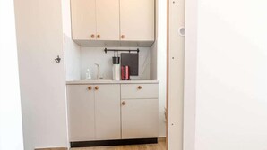 A compact kitchen with white cabinets, a countertop, and a black backsplash. - Old Town Rooms Ljiljana (Pula)