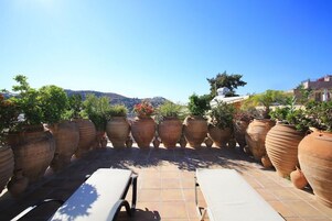 Una terrazza sul tetto con fioriere in terracotta e poltrone relax.