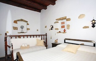 Un dormitorio con dos camas de madera, un adorno de pared de piedra, una imagen de un molino y una lámpara fijada a la pared.