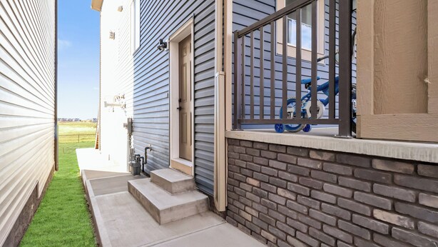 A residential building with a brick exterior, a small set of concrete steps leading to a door, and a blue bicycle parked on a balcony. - Modern 2 BR walkout suite|5 mins to Airport
Entire guest suite in Calgary,Canada (Calgary)
