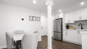 A modern kitchen with white cabinets, a stainless steel refrigerator, and a dining area with a white table and chairs. - Modern 2 BR walkout suite|5 mins to Airport
Entire guest suite in Calgary,Canada (Calgary)
