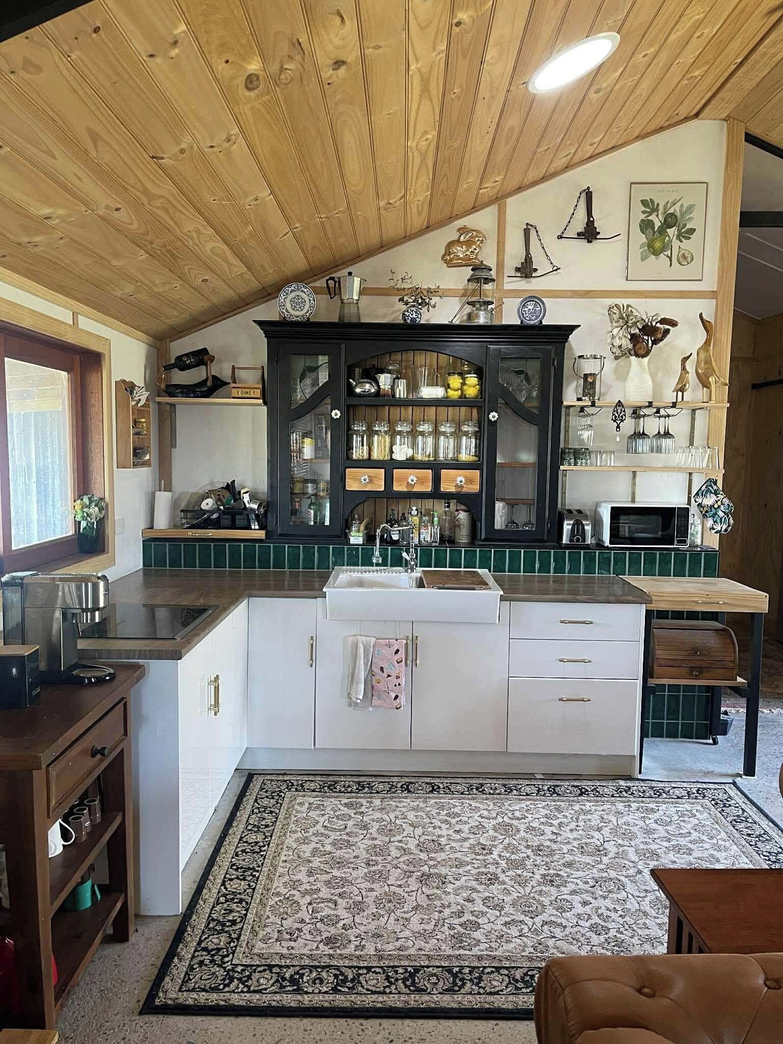Uma cozinha com teto de madeira, uma ilha central e um tapete estampado.