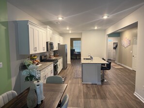 Cocina moderna con gabinetes blancos, refrigerador de acero inoxidable y encimera de granito.