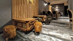 Interior de restaurante con paredes de paneles de madera, suelo de mármol y diferentes opciones de asientos, incluyendo mesas y sillas.