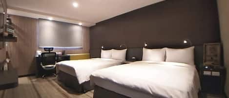 A hotel room with two beds, a desk, a chair, and a small table.