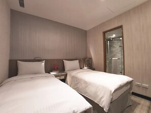 Habitación de hotel con dos camas, una mesita de noche, un espejo y zona de ducha.