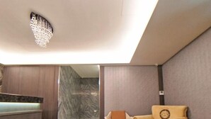 Un interior moderno con suelo de mármol, un sofá, una mesa de centro de madera y una lámpara decorativa en el techo.