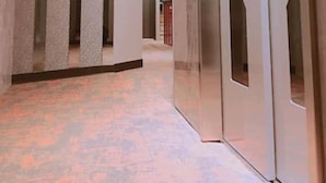 Un pasillo de diseño moderno, con una pared curva, una columna y una puerta con un motivo geométrico.