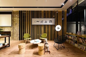 Un interior moderno con suelo de madera, sillas verdes, una silla negra, una mesa redonda y una estantería.