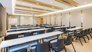 A conference room with multiple tables and chairs, a whiteboard, and a door in the background. - Atour Hotel (Hangzhou)
