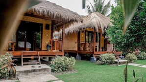 A bungalow-style hotel with thatched roofs, a wooden deck, and a well-maintained garden. - Aldi's Bungalow and Homestay (Kuta)