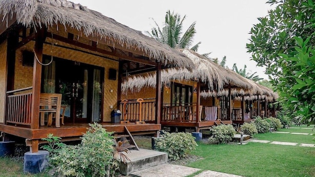 A row of thatched-roof cottages with wooden balconies and steps leading to the entrance. - Aldi's Bungalow and Homestay (Kuta)