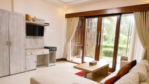 A hotel room with a bed, a desk, a TV, and a sliding glass door to a balcony. - Aldi's Bungalow and Homestay (Kuta)