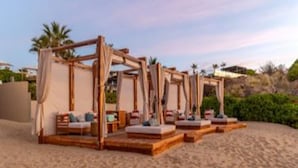 A beachside resort with wooden cabanas, each with a bed and a small table. - Zadun, a Ritz-carlton Reserve (San José del Cabo)
