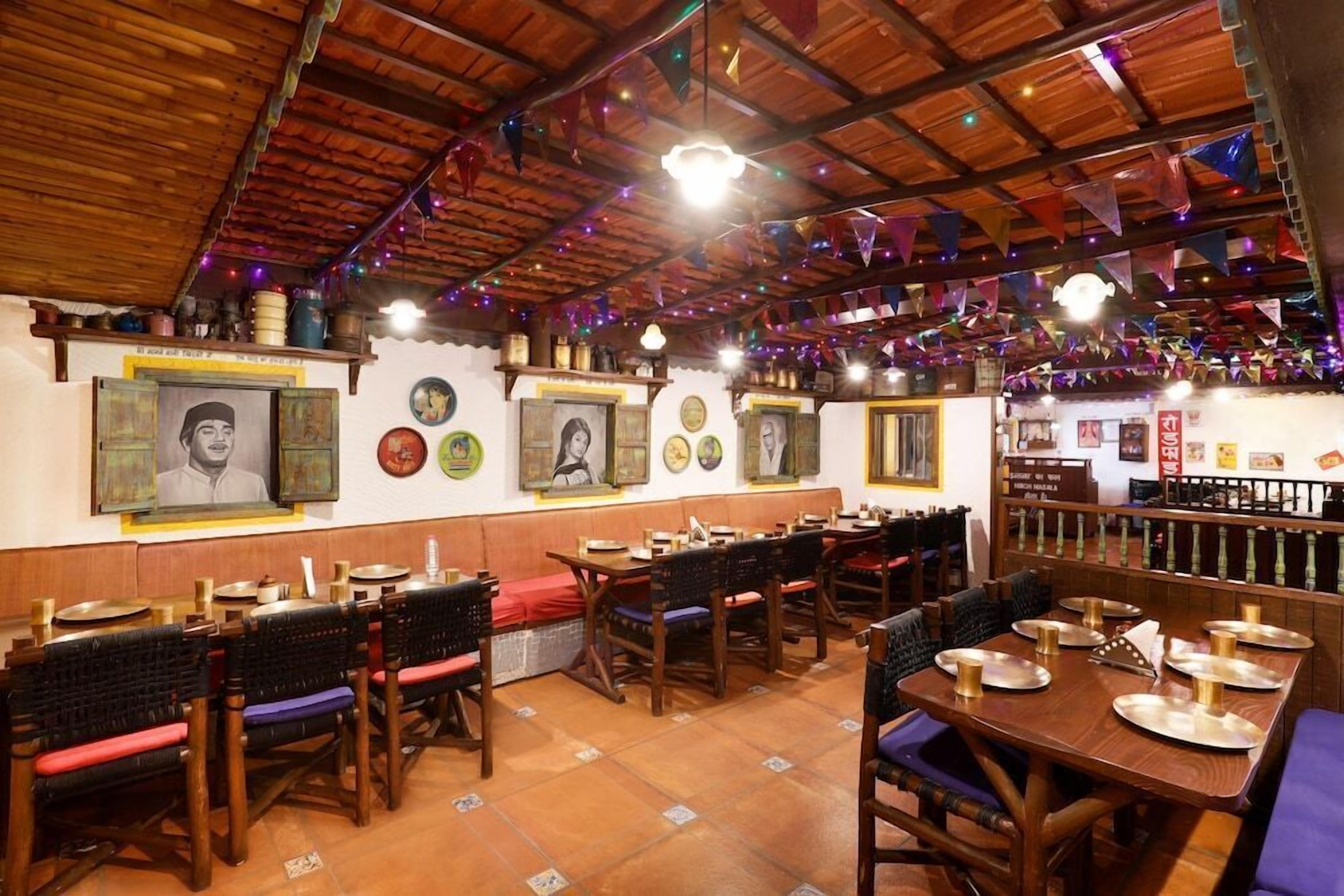 A restaurant with wooden tables and chairs, a tiled floor, and a high ceiling with colorful decorations.