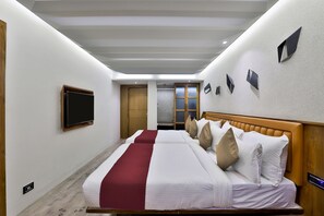 A hotel room with a bed, a TV, a wardrobe, and a mirror. - Keys Select by Lemon Tree Hotels (Ahmedabad)