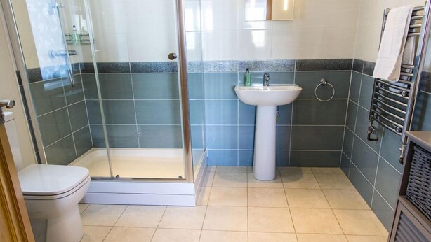 Une salle de bain avec une douche à parois de verre, un lavabo blanc et des toilettes.