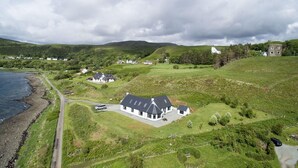 Une propriété située sur la côte, comprenant une grande maison, un bâtiment plus petit et une tour.