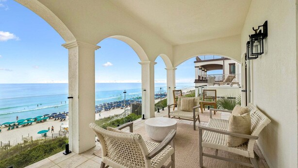 A balcony with wicker furniture, a stone table, and a view of the beach and ocean. - GULF-FRONT w/ Private Beach! Private Pool, Hot Tub! Sleeps 24! (Rosemary Beach)