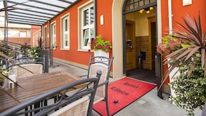 A covered outdoor area with a red carpet leading to a door marked "Hotel Zimmer". - Hotel Restaurant Löwen (Rust)