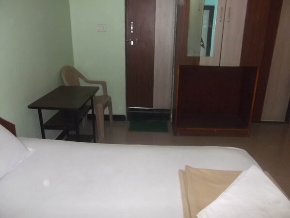 A room with a bed, a desk, a chair, and a wardrobe. - Hotel Oasis (Daund)