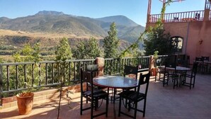 A terrace with a table and chairs, potted plants, and a view of mountains. - Dar Soulaimane Ourika (Marrakech)