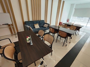 A modern meeting room with a dark wooden table, wicker chairs, a blue sofa, and a whiteboard. - Bangi Business Hotel (Bandar Baru Bangi)