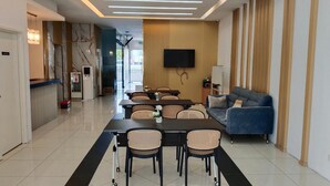 A modern living room with a dining area, a sofa, a flat-screen TV, and a staircase leading to another level. - Bangi Business Hotel (Bandar Baru Bangi)