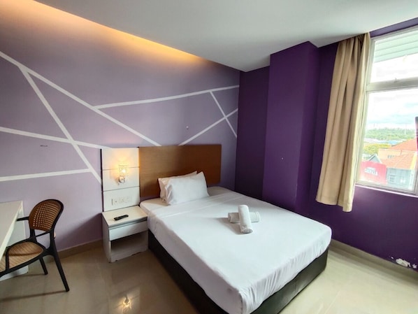 Une chambre d’hôtel avec un lit, un bureau, une chaise et une fenêtre donnant sur un paysage agréable.