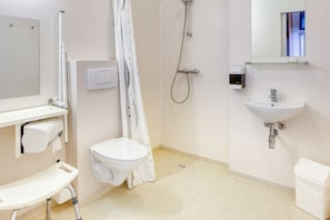 Et badeværelse med toilet, brusebad, vask og spejl.