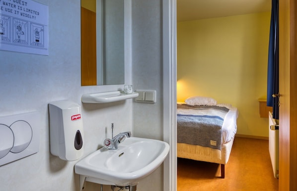 Et badeværelse på et hotel med vask, spejl og sæbedispenser.
