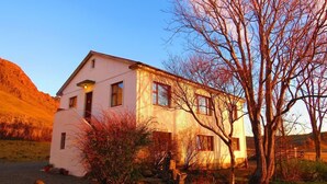 Un bâtiment blanc à deux étages, doté d’un toit en pente, d’un petit porche et d’une grande fenêtre.