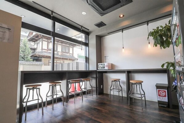 Un espace bar moderne avec des tabourets en bois, un four à micro-ondes et une vue sur une architecture traditionnelle.