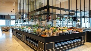 A modern buffet setup with various food items and plants. - West Lagoone Hotel (Netanya)