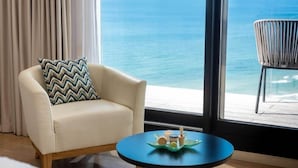 A room with a view of the ocean, a chair with a patterned pillow, and a small table with a decorative item. - West Lagoone Hotel (Netanya)