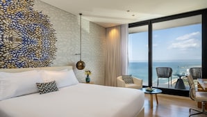 A modern hotel room with a large bed, a view of the ocean, and a balcony with seating. - West Lagoone Hotel (Netanya)