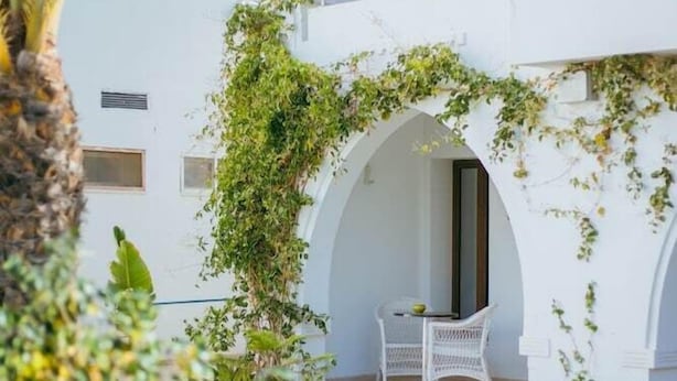 A white building with arched balconies and a covered outdoor seating area. - Palm Djerba (Mezraia)
