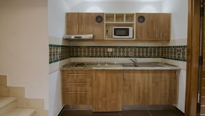 A compact kitchen with wooden cabinets, a microwave, and a tiled backsplash. - Palm Djerba (Mezraia)