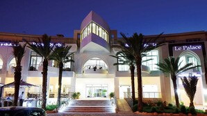 A hotel with a central atrium, palm trees, and a sign for 'Le Palace'. - Palm Djerba (Mezraia)
