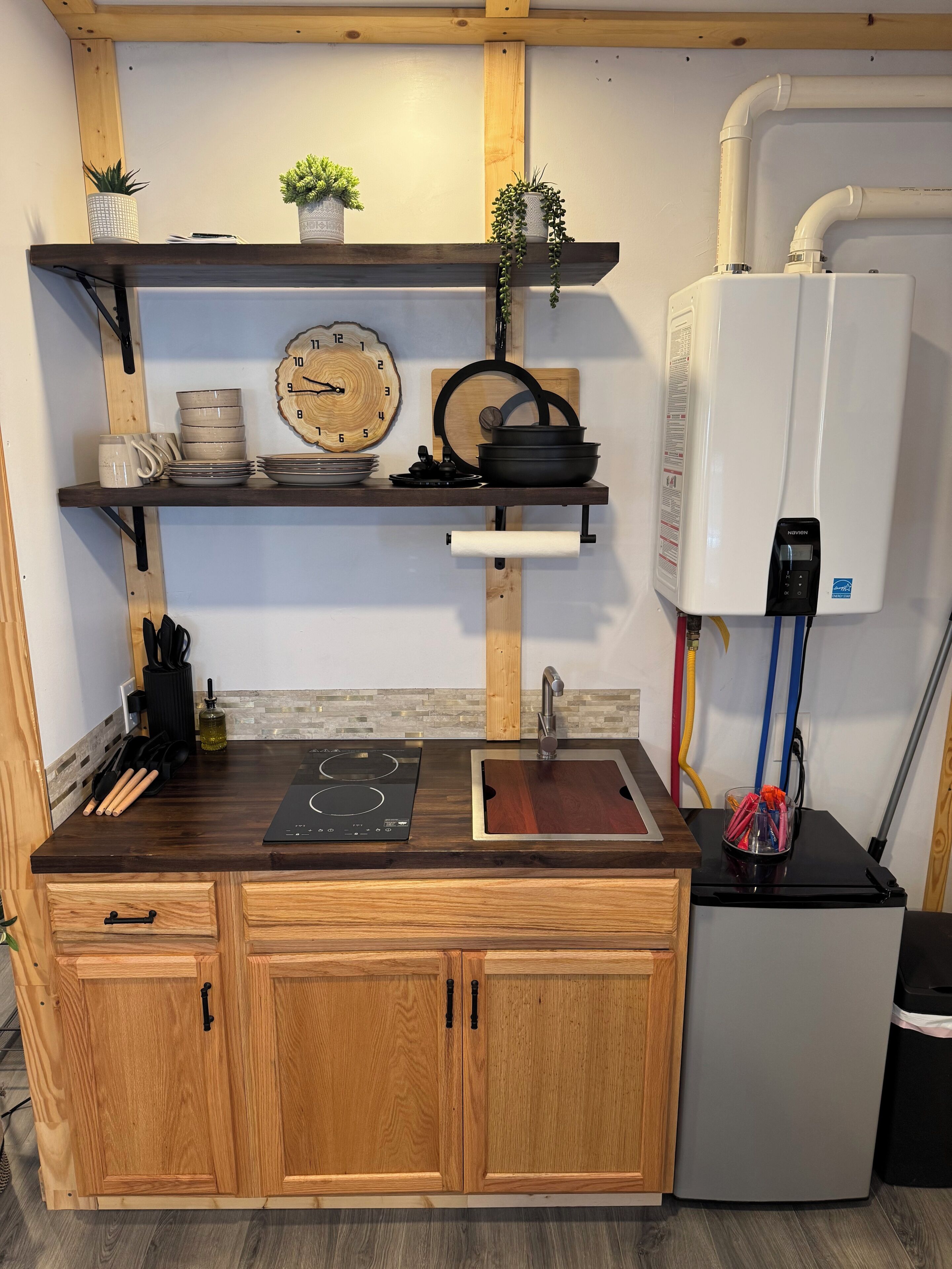 A compact kitchen with a built-in stove, wooden cabinets, a sink, and a white water heater.