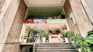 Entrada de un hotel con un letrero que dice "The Jade" y una tienda RedDoorz debajo.