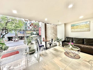 Un interior modern amb un sofà, una taula de centre i vista al carrer.