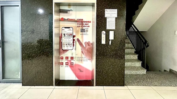 Entrada de hotel con un quiosco de servicio RedDoorz, una escalera y un suelo de baldosas.