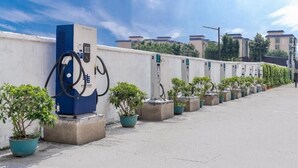 A row of potted plants and a blue electric vehicle charging station along a concrete pathway. - Vyluk Hotel Guangzhou Baiyun International Airport (Guangzhou)
