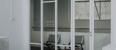 A room with a sliding glass door leading to a balcony with two chairs and a small table.