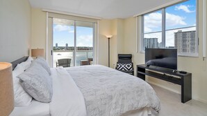 A modern bedroom with a large bed, a TV on a stand, and a view of the city through large windows. - Entire condo in Sunny Isles Beach, Florida, United States (Sunny Isles Beach)