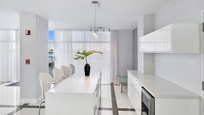 A modern hotel lobby with a long reception desk, white chairs, a potted plant, and a large window with sheer curtains. - Entire condo in Sunny Isles Beach, Florida, United States (Sunny Isles Beach)