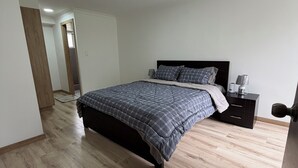 Une chambre à coucher avec un lit, une table de chevet, une lampe et un plancher en bois.