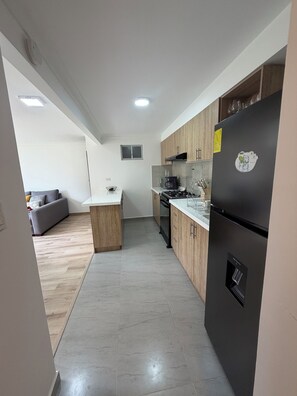 Una cocina moderna con armarios de madera, un refrigerador negro y un horno empotrado.